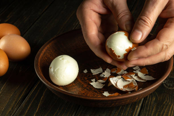 istock Close-up of a man hands holding a boiled egg. Peeling eggs from the shell. Cooking a delicious dinner with boiled eggs. 1940321033