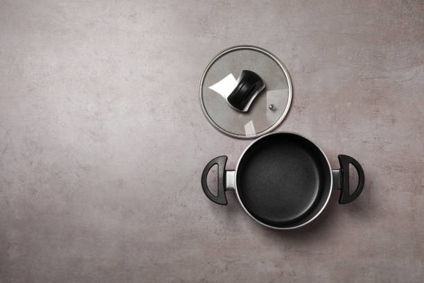 istock One empty black pot and glass lid on grey textured table, flat lay. Space for text 1940340160