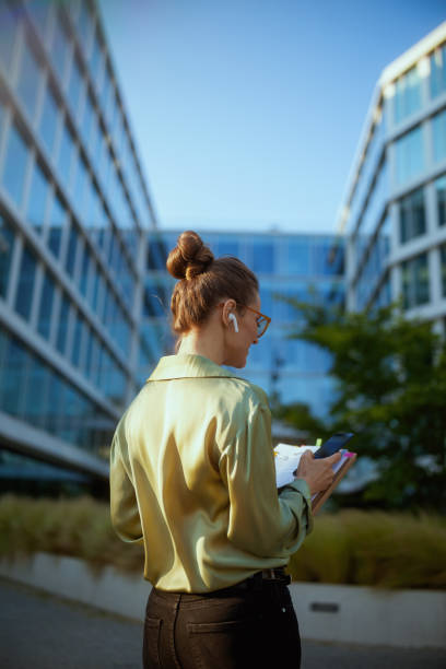 istock modern female employee near office building using smartphone 1940361147