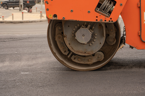 Vibratory asphalt rollers compact the new asphalt surface of the highway. Road authorities are building a new highway