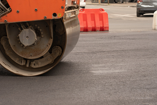 Vibratory asphalt rollers compact the new asphalt surface of the highway. Road authorities are building a new highway