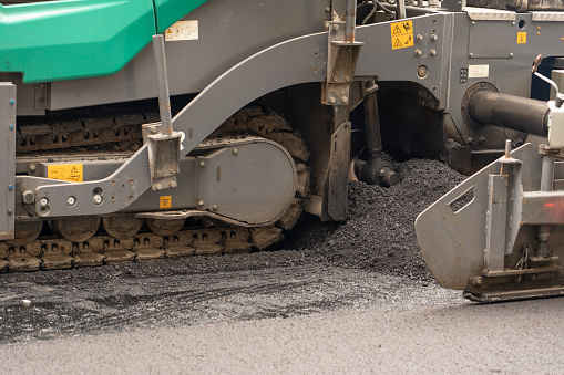 Vibratory asphalt rollers compact the new asphalt surface of the highway. Road authorities are building a new highway