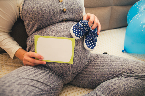 A pregnant woman holding up a blank sign stock photo