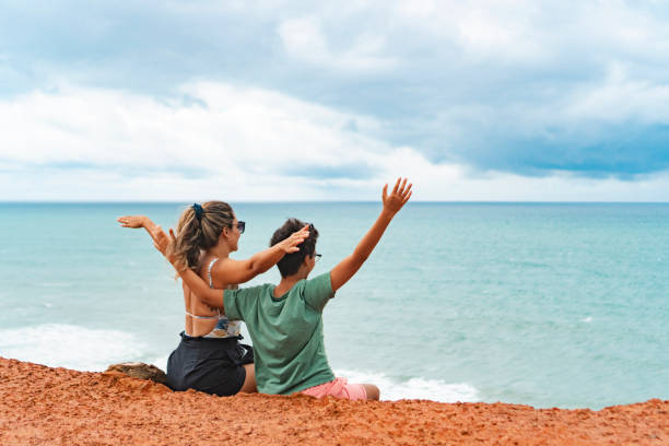 istock Mother and son with arms raised on cliff 1940385985
