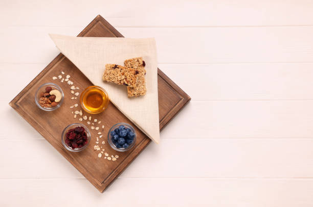 istock Tasty granola bars served on white wooden table, top view. Space for text 1940399644