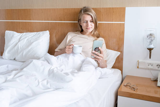 istock Woman using smartphone lying in bed and drinking coffee 1940403874