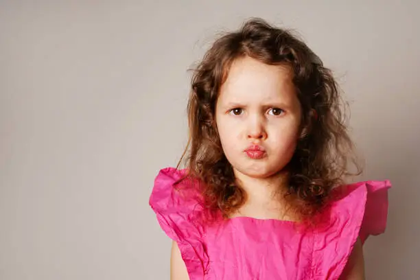 Photo of Beautiful angry little child girl looking at you. the child puffed out her cheeks