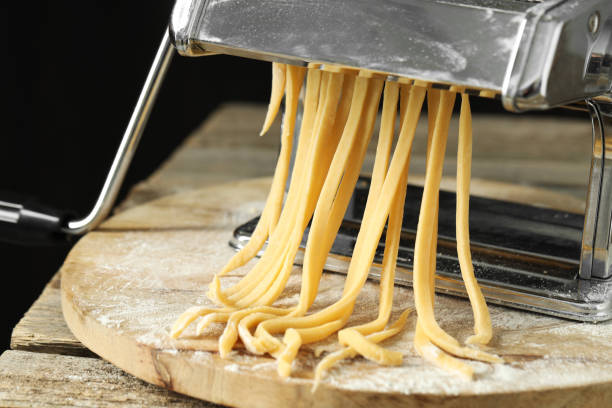 istock Pasta maker with raw dough on wooden table 1940435680