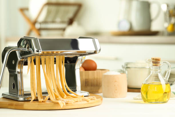 istock Pasta maker with raw dough and ingredients on white wooden table 1940436754