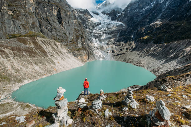 istock Female trekker dressed bright red jacket on the rock enjoying a glacier falling in high altitude Sabai Tso glacial lake cca 4350m. Makalu Barun National Park, Mera peak climbing route, Nepal. 1940439969