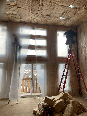 Construction workers insulate and vapour barrier house