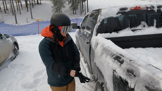Young man stands beside pickup truck in winter snow