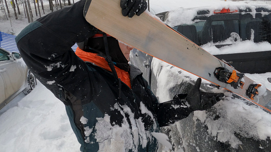 Young man removes skis from vehicle at ski resort