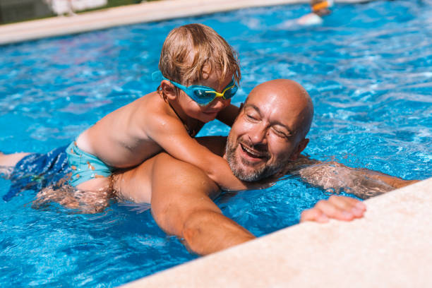 istock dad swims with his son in the pool playing 1940476366