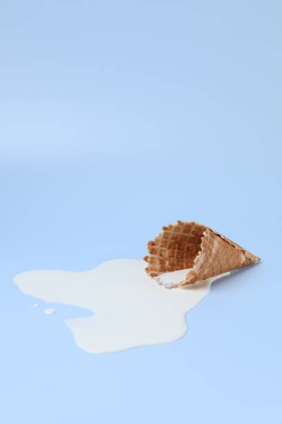 istock Melted ice cream and wafer cone on light blue background, space for text 1940484208