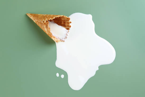istock Melted ice cream and wafer cone on green background, top view 1940484747