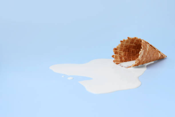 istock Melted ice cream and wafer cone on light blue background, space for text 1940484752