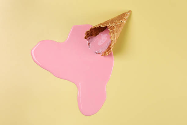 istock Melted ice cream and wafer cone on pale yellow background, top view 1940486360