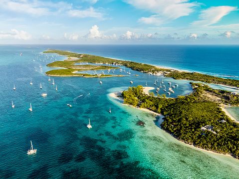 Aerial view of Shirley Heights lookout. Landscape with harbor bay, sea and mountains, boats in the harbor and the white sand beach of Antigua and Barbuda. Bright image with clouds in the sky.