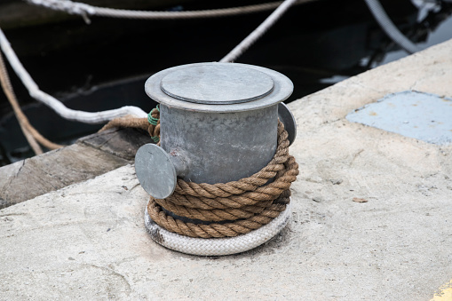 Metal dock mooring pole with rope for securing fishing boats closeup
