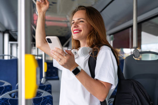 istock Attractive brunette woman with red lips using her smart phone while traveling by city bus. 1940605564