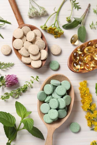 istock Different pills, herbs and flowers on white wooden table, flat lay. Dietary supplements 1940610742
