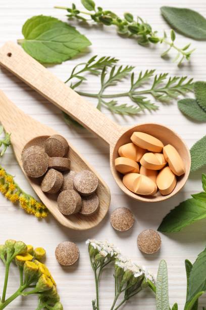 istock Different pills, herbs and flowers on white wooden table, above view. Dietary supplements 1940611793