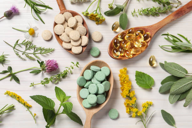 istock Different pills, herbs and flowers on white wooden table, flat lay. Dietary supplements 1940612889