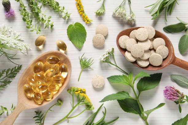 istock Different pills, herbs and flowers on white wooden table, flat lay. Dietary supplements 1940612918