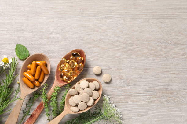 istock Different pills, herbs and flowers on wooden table, flat lay with space for text. Dietary supplements 1940614512