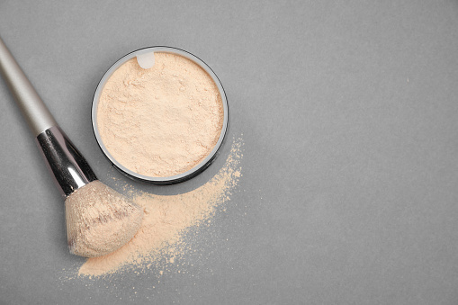 Loose face powder and makeup brush on light grey background, flat lay. Space for text