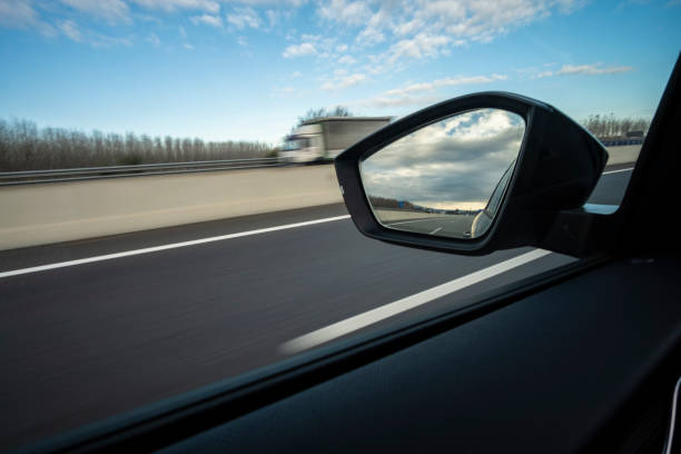 istock Left side window car scene while driving on a highway with mirror looking backwards on a cloudscape sky 1940670986