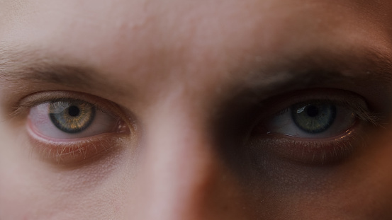 Extreme close-up colored eyes of young blonde man looking at camera