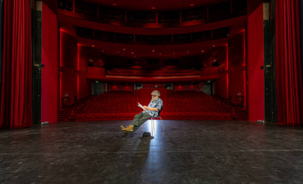 Actor, director rehearsing his lines on empty stage, seen from stage point of view.