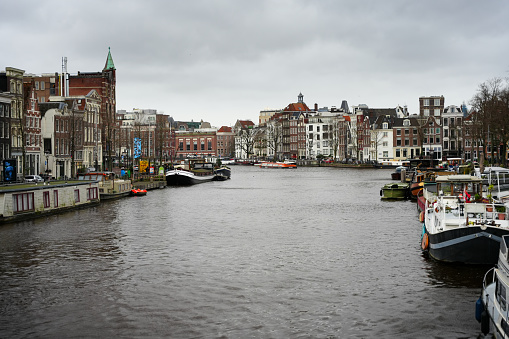 Amsterdam, Netherlands - December 28, 2023: View to canal in cloudy day.