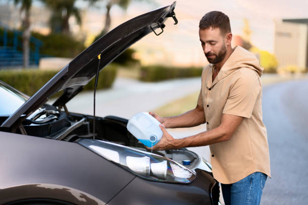 istock Man pouring windshield washer fluid for clearing car. Car service concept 1940716612