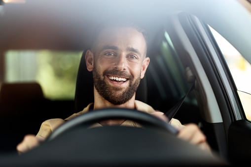 Portrait of handsome smiling latin man driving a car. Car sharing concept