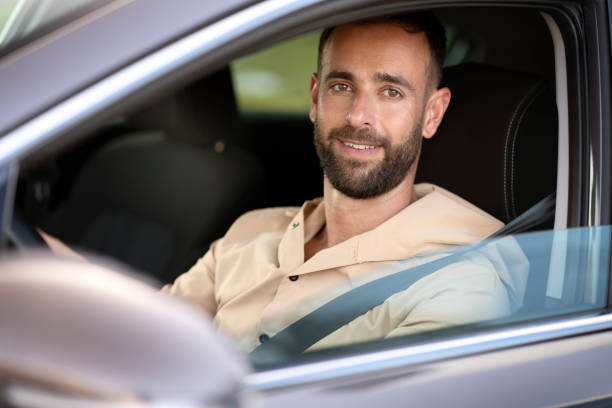 istock Confident smiling latin man driving a car looking at camera. Car sharing concept 1940717125