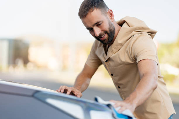 istock Bearded man cleaning his car using micro fiber cloth. Car washing service concept 1940717149