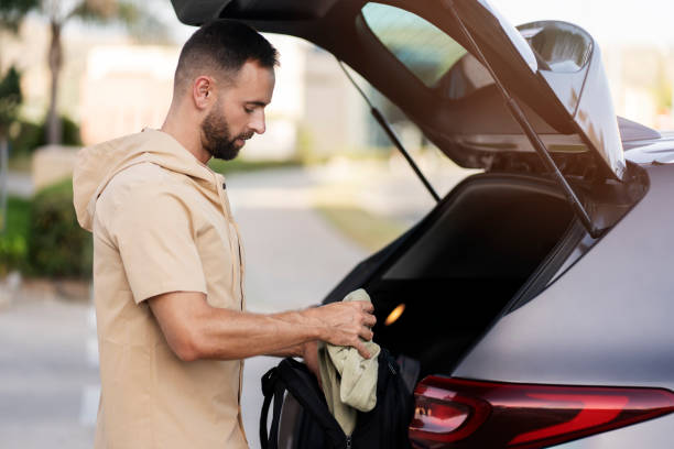 istock Latin man loading bag in car trunk. Driver planning road trip 1940717687