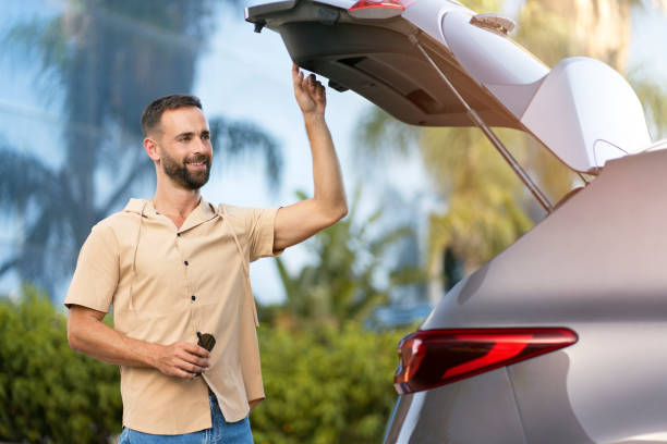 istock Latin man driver opening car trunk planning road trip 1940717700
