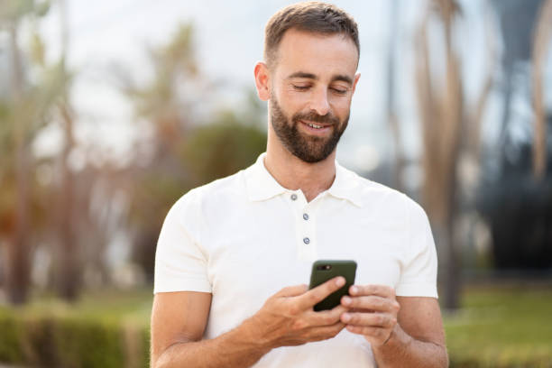 istock Handsome latin man using mobile app shopping online on the street 1940717708