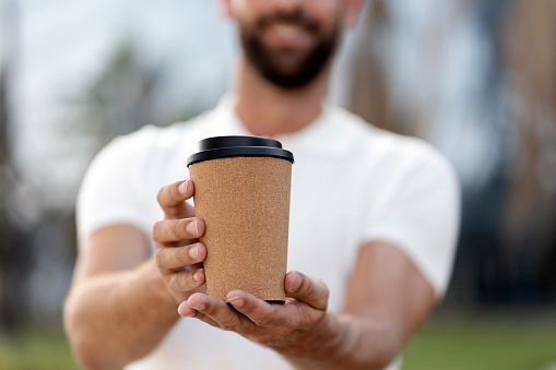 Close up of smiling man hands holding cup of coffee, selective focus Coffee break, take away drink concept