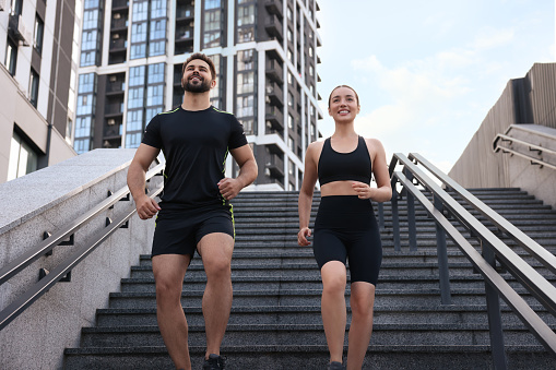 Healthy lifestyle. Happy couple running on steps outdoors, low angle view
