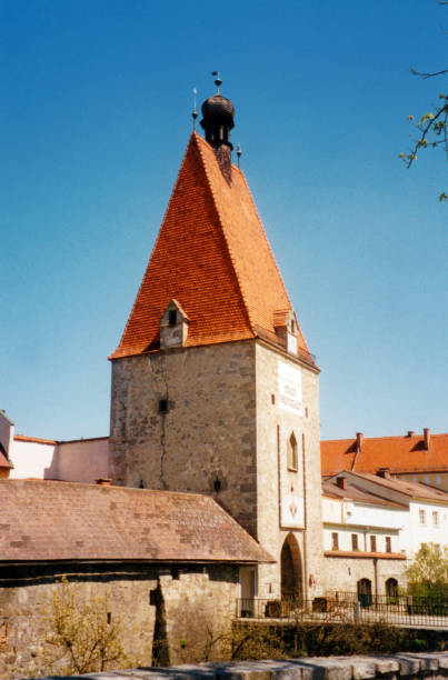 A dramatic upward perspective of a medieval stone fortification tower at Gori Fortress (Goristsikhe) in Georgia. The image highlights the rugged texture of the cobblestone and mortar masonry against a bright blue sky with soft clouds. This historic citadel, located on a hill in the center of Gori, showcases classic Caucasian military architecture and historical defense structures.