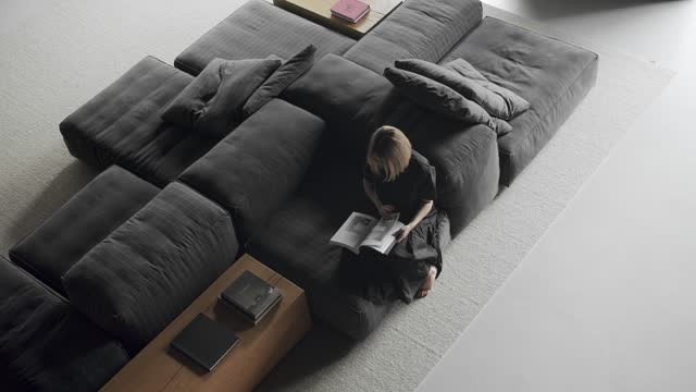 Overhead view of woman sitting on comfort modular sofa at modern apartment