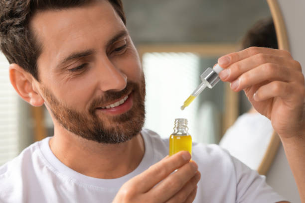 istock Smiling man with cosmetic serum indoors, closeup 1940739777