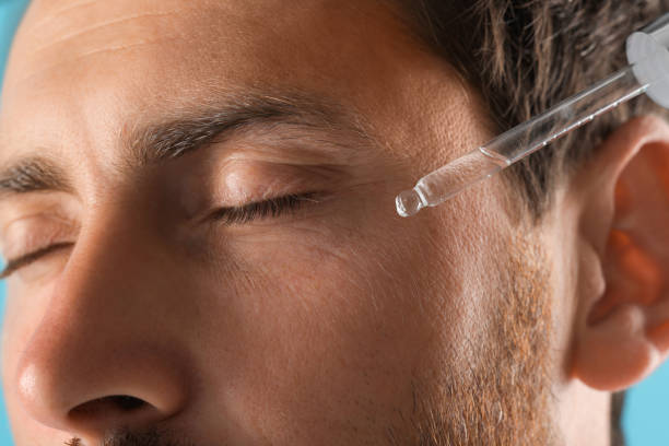 istock Handsome man applying cosmetic serum onto his face, closeup 1940739784