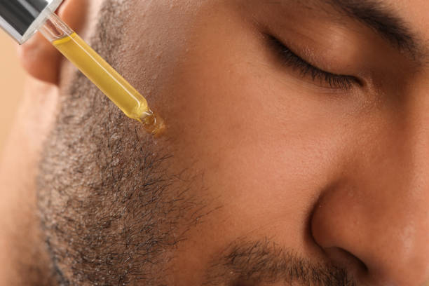 istock Man applying cosmetic serum onto face, closeup 1940740824