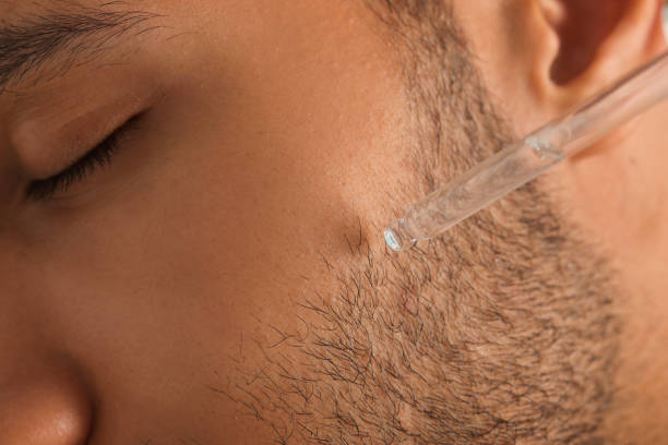 istock Man applying cosmetic serum onto face, closeup 1940741254